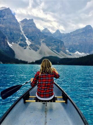 Woman who has learned how to stop doubting herself, rowing independently in a canoe.